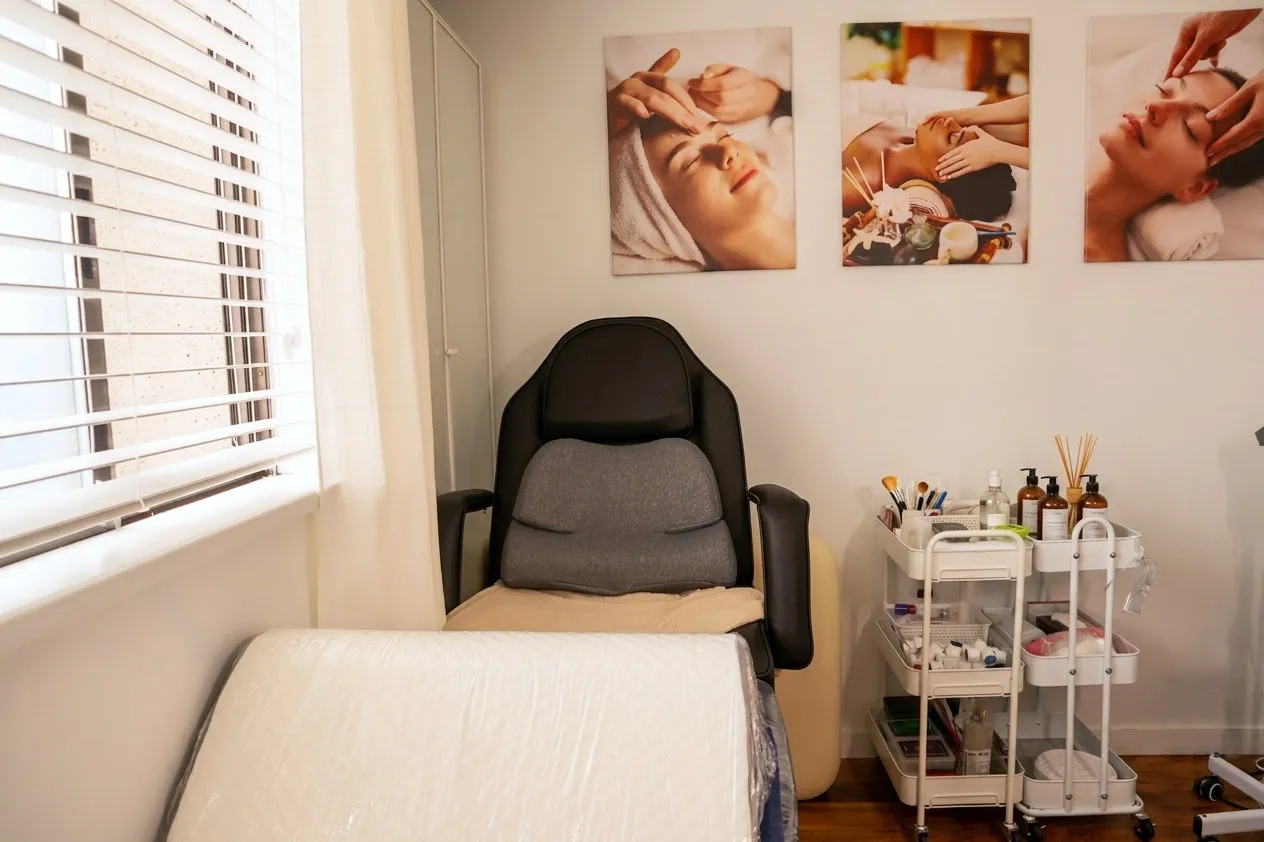 The treatment bed and reclining chair by the window, with a trolley of products beside them