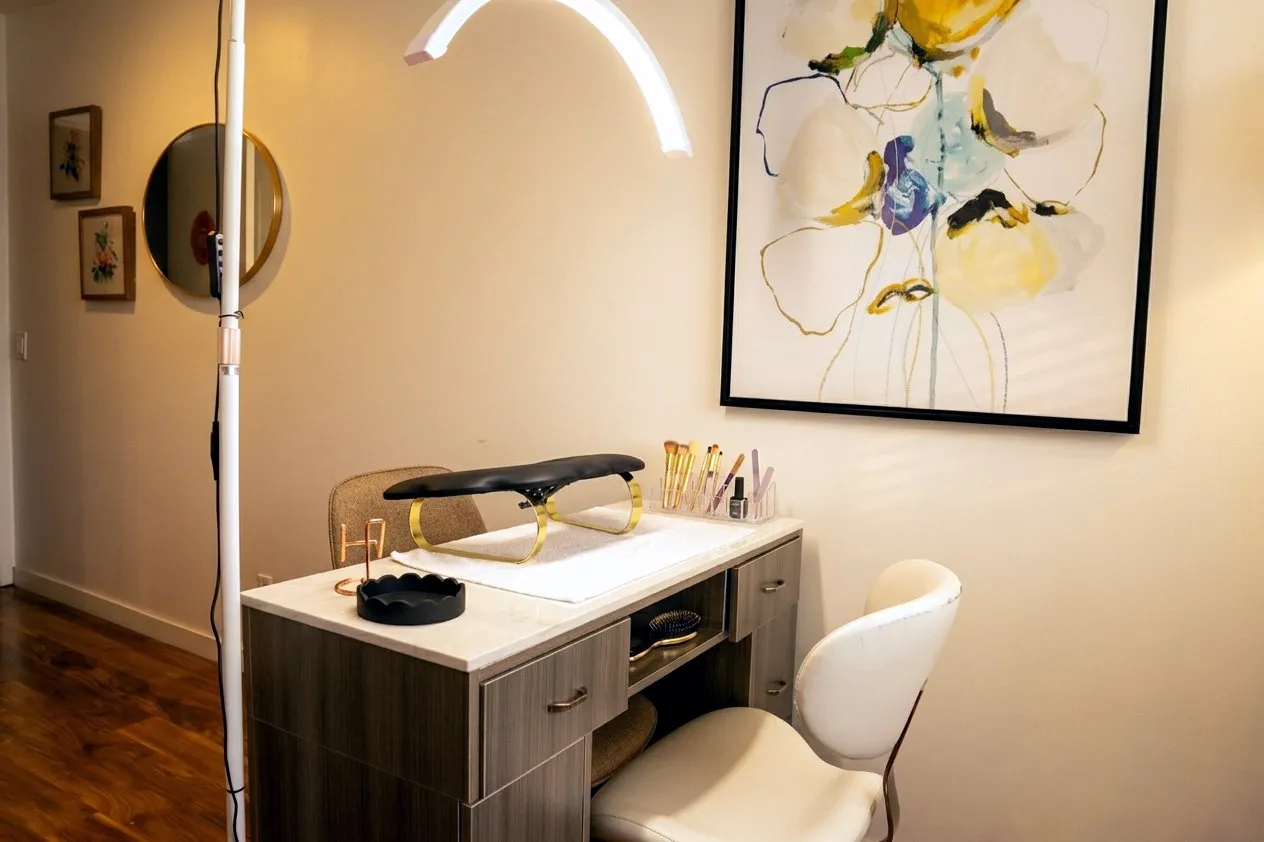 The manicure desk in the studio, with a ring light over it and a large abstract painting on the wall behind