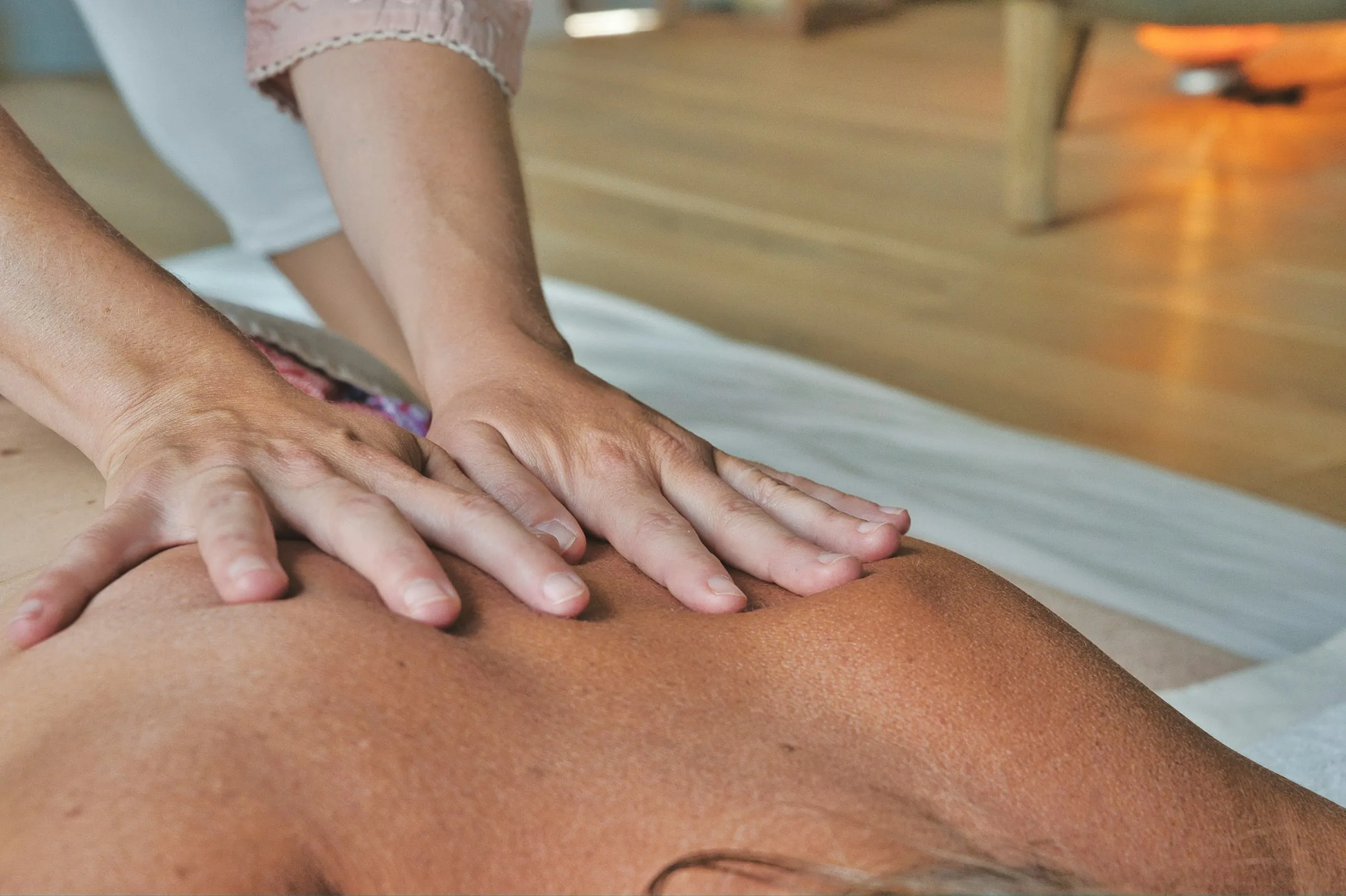 A therapist's hands working across a client's back